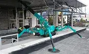 Maeda MC285C mini spider crane positioned on a construction site with outriggers extended