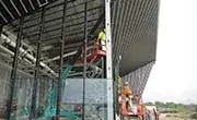 Maeda MC405C mini spider crane installing structural components beneath a steel roof